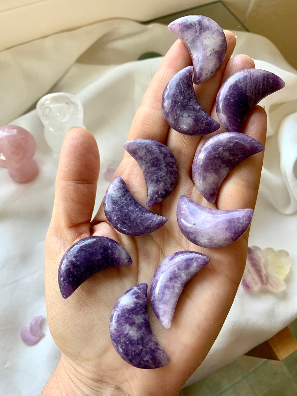 Purple Lepidolite Crescent Moon shaped crystal carvings shown on my hand for scale