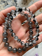Two Black Tourmaline in Quartz bracelets worn on a hand, showing clarity and fine tourmaline inclusions