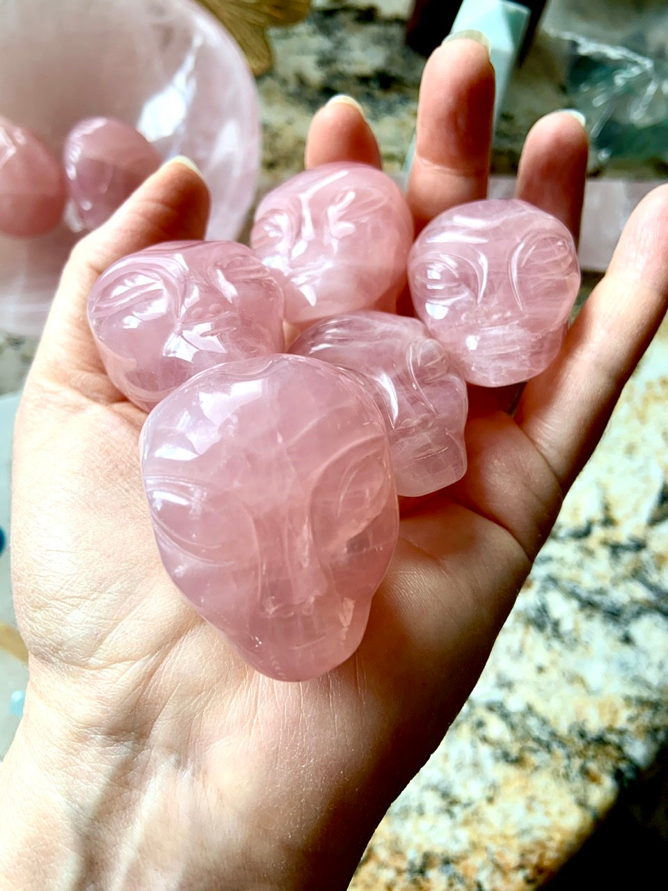 Rose Quartz alien head carving with large eyes and defined brow, shown in a pink crystal bowl on altar