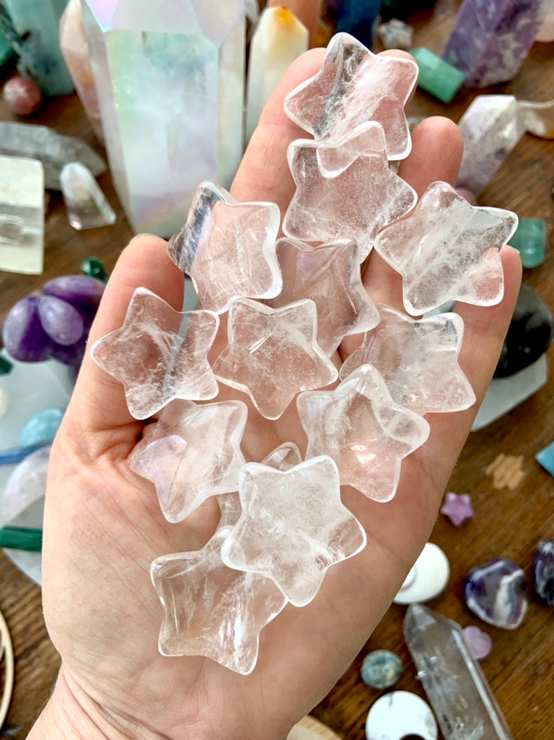 a handful of clear quartz crystal stars shown with a crystal collection in the background