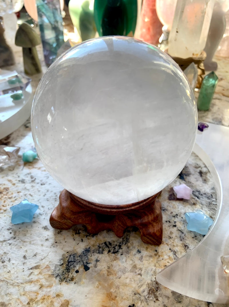 an optical calcite sphere on a wood stand with a crystal collection in the background