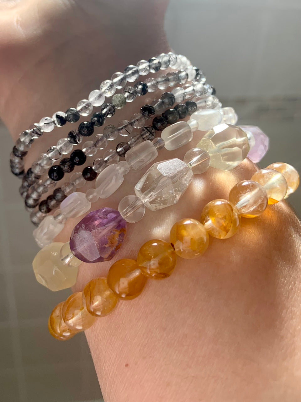 Crystal bracelet stack featuring Golden Healer Quartz, faceted amethyst + quartz, white moonstone, and black tourmaline in quartz