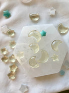 Overhead view of mini citrine stars and moons on selenite plate with celestial mini crystals — joyful citrine carvings for chakra healing