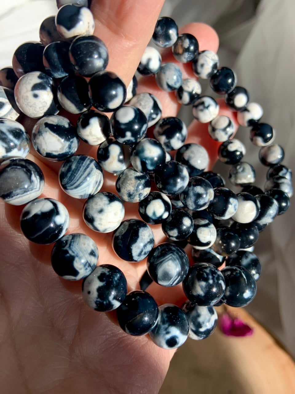 Closeup of stacked Orca Agate bracelets in assorted sizes, showing high polish and unique swirling patterns