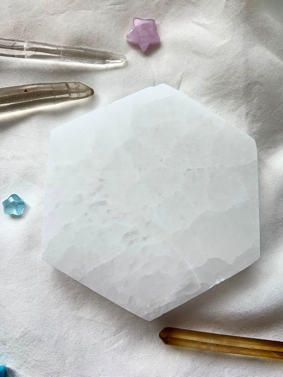 Overhead view of a Selenite Hexagon Charging Plate with clear quartz points, citrine points, and mini crystal stars