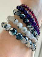 Stack of healing crystal bracelets featuring Orca Agate, Rainbow Moonstone, Amethyst, and Garnet for chakra alignment and emotional healing
