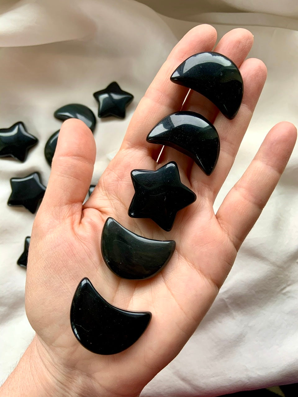 Black Obsidian moon crystals with obsidian star on hand — glossy black carvings for energetic shielding and grounding energy