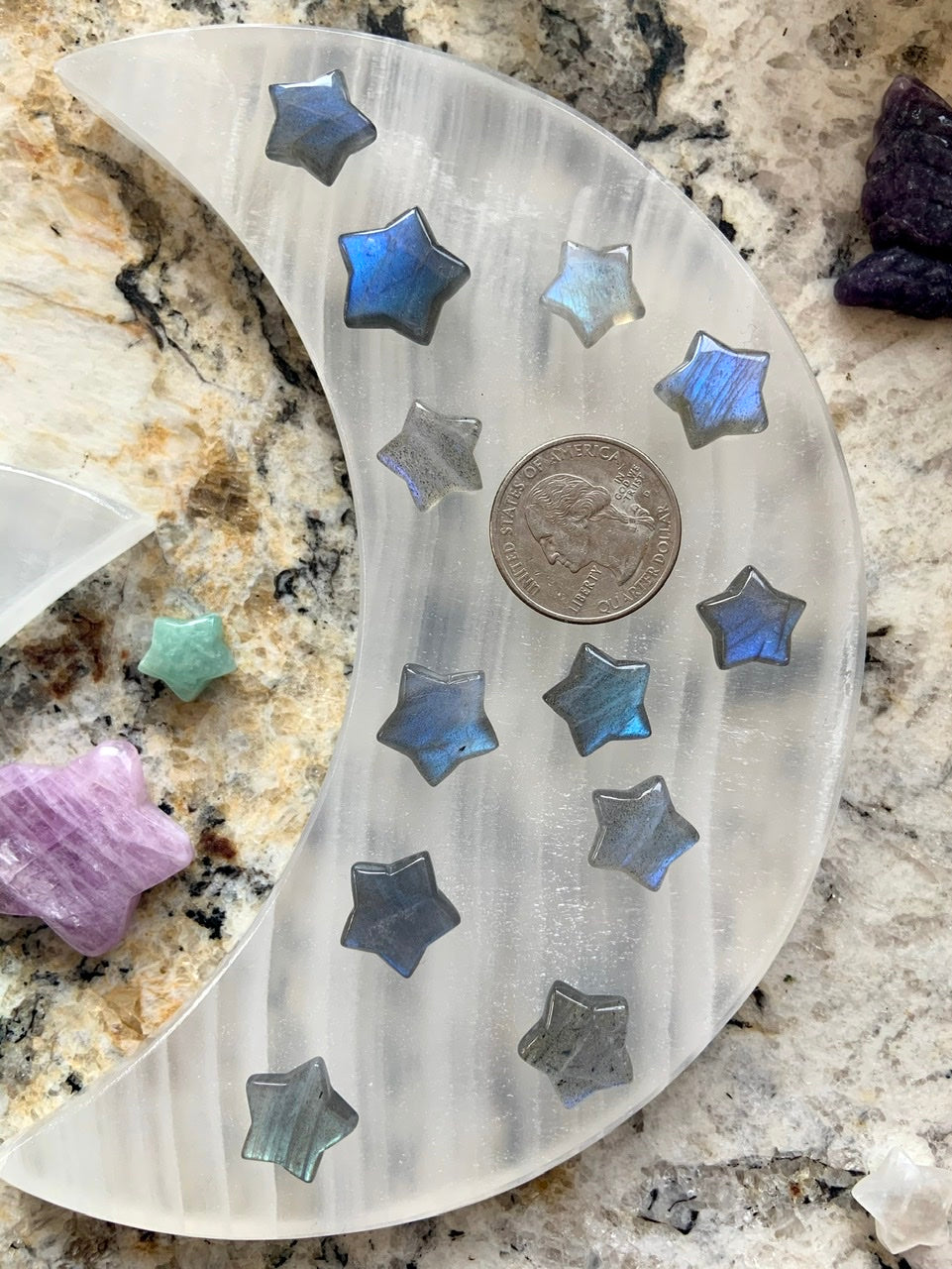 White moon plate with pastel Labradorite mini stars and a quarter for scale — dreamy crystal display with celestial carvings for intuitive energy work.