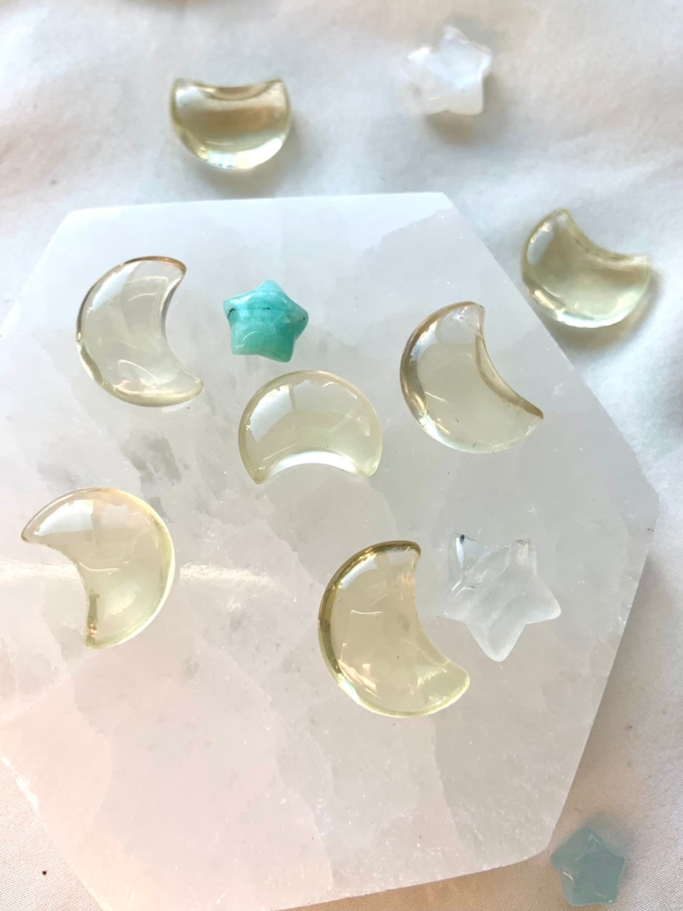 Citrine moons and crystal stars arranged on a selenite plate — mini citrine carvings for healing rituals and energy work