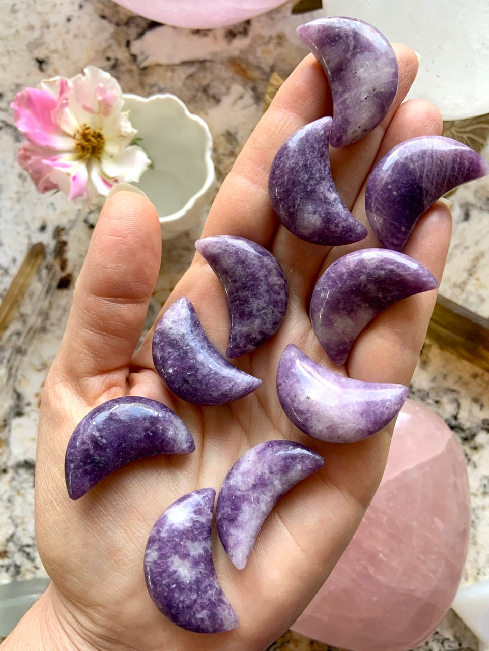 Purple Lepidolite Crescent Moon shaped crystal carvings shown on my hand for scale