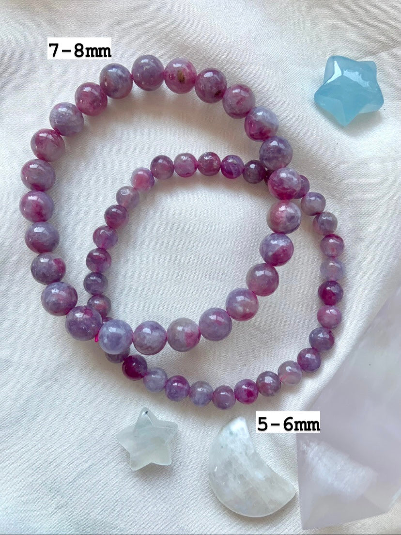 Overhead of 2 Unicorn Stone bracelets on white silk with celestial crystals — marked with 7–8mm and 5–6mm bead sizes, shown with Blue Lace Agate + Aquamarine.