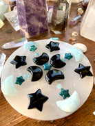 Crystal grid with Obsidian crescent moons + Black Obsidian Stars, Blue Apatite stars & Aquamarine moons on a selenite charging plate — energy tools for grounding & clarity