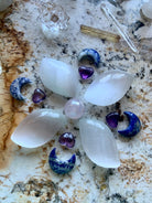 Flower-shaped crystal grid with selenite petals, Lapis Lazuli moons, and Aura Rose Quartz centerpiece — sacred layout for spiritual alignment