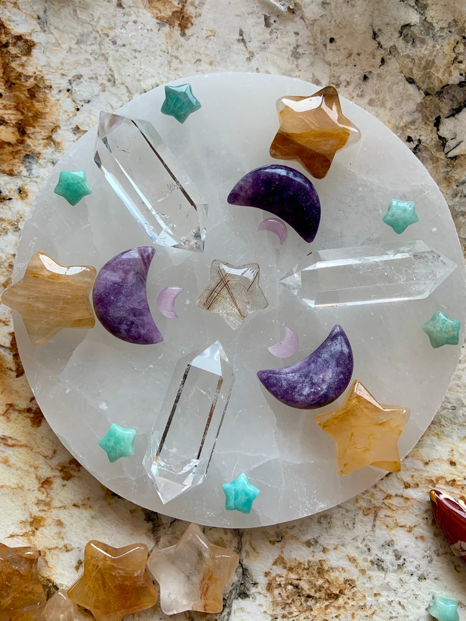 Crystal grid on round selenite plate with clear quartz double terminated points, golden healer stars, lepidolite moons, amazonite stars, and golden rutile star in center