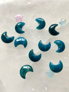 Blue Apatite Crescent Moons on selenite plate with other mini crystals — throat chakra carvings for clarity, truth & energetic flow.