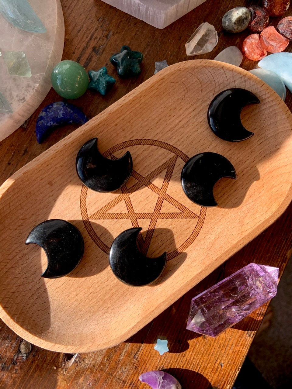 Array of Black Obsidian moon crystals on a wood tray — celestial carvings for aura protection and stability