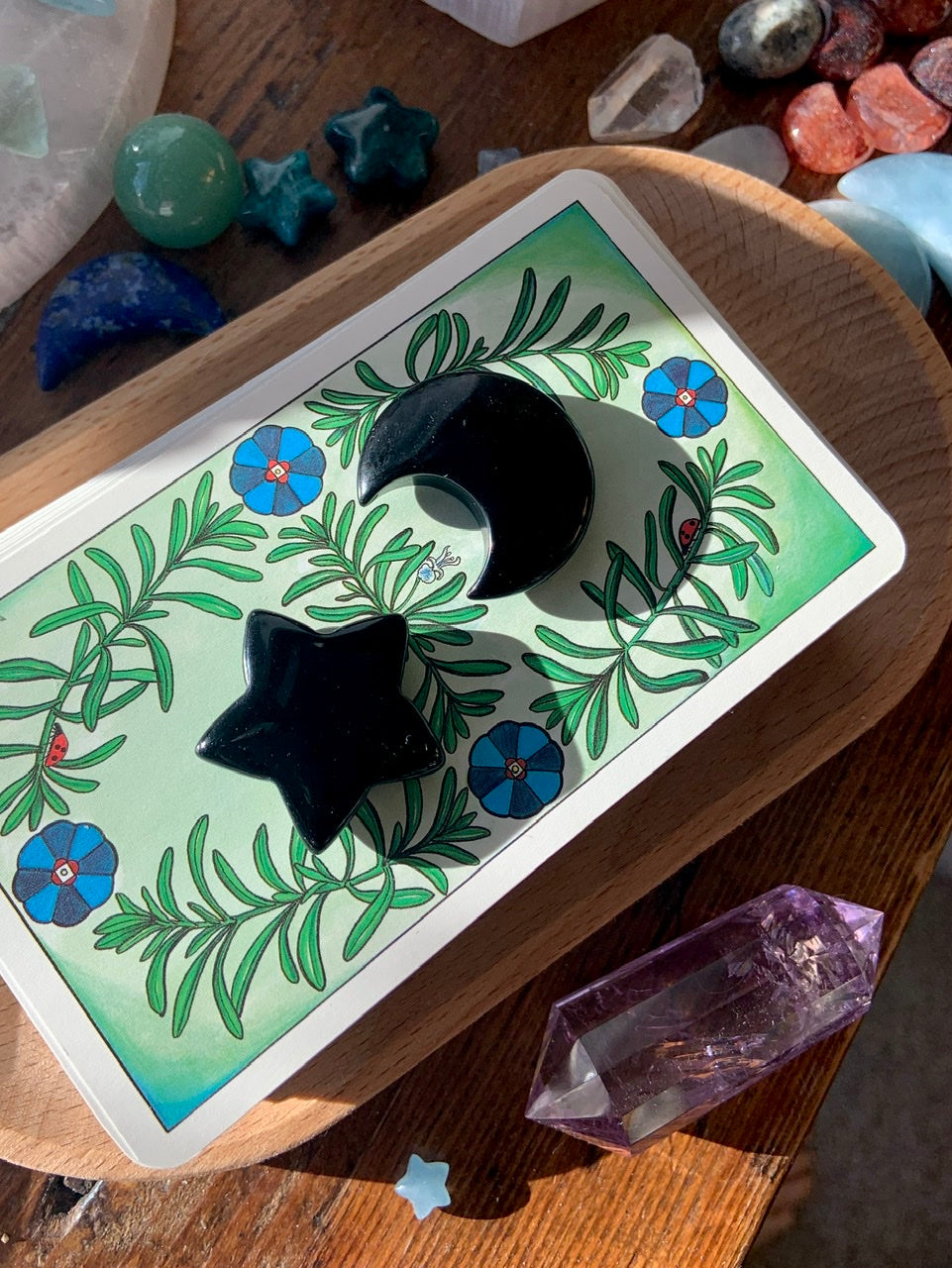 Black Obsidian moon and star carvings displayed on a stack of tarot cards — protective crystal décor for grounding, Root Chakra healing & energy work
