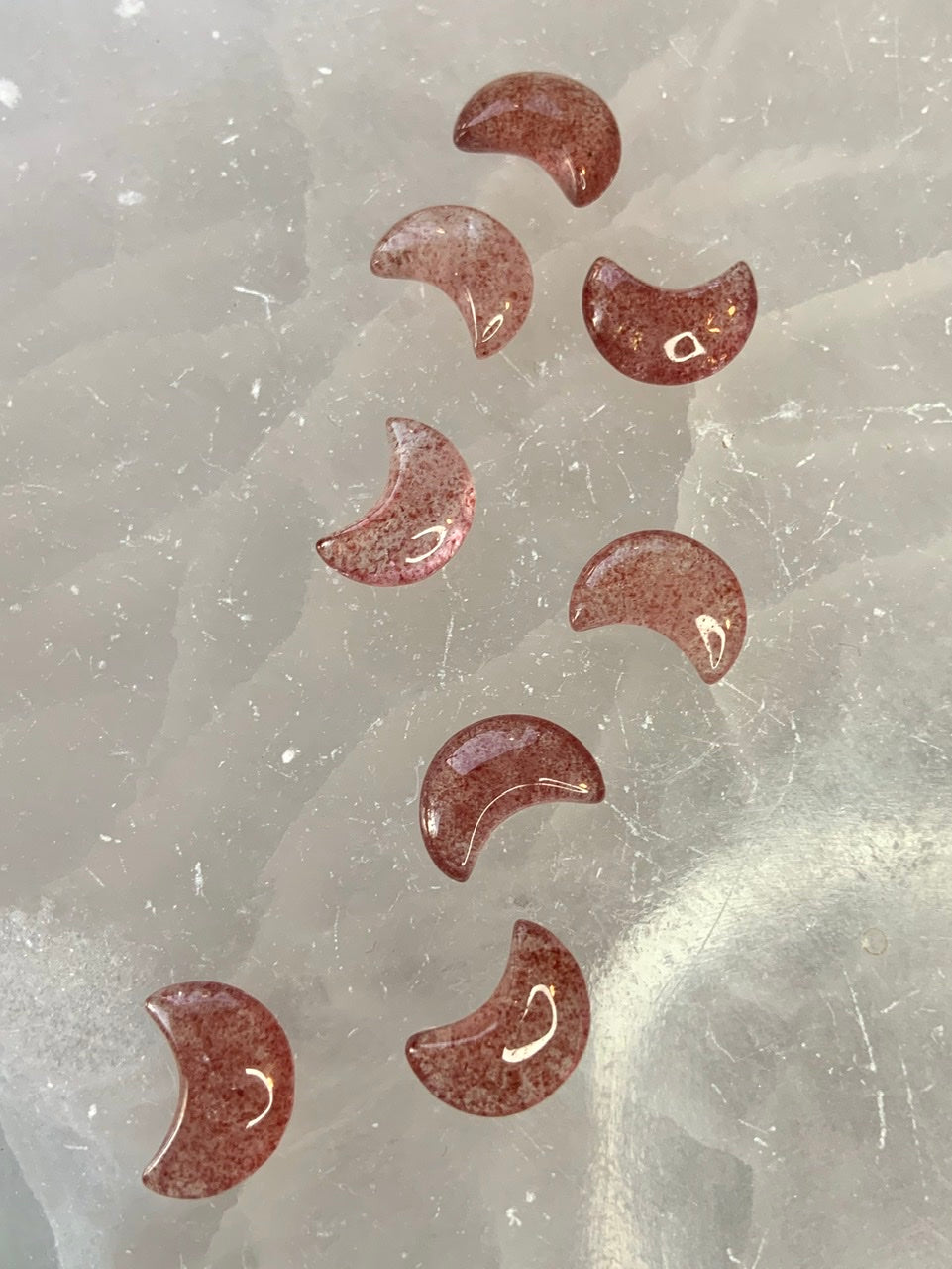 Strawberry Quartz mini moons arranged on white selenite — heart chakra crystals for love, clarity, and high-vibe altar decor