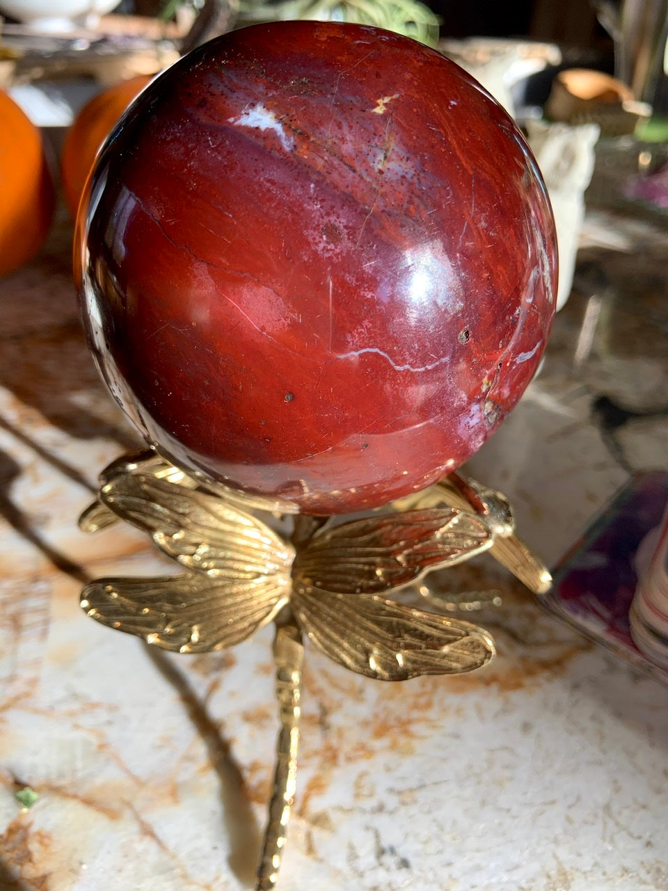 Gold dragonfly crystal ball stand holding a red ocean jasper sphere — unique holder for crystal sphere display.