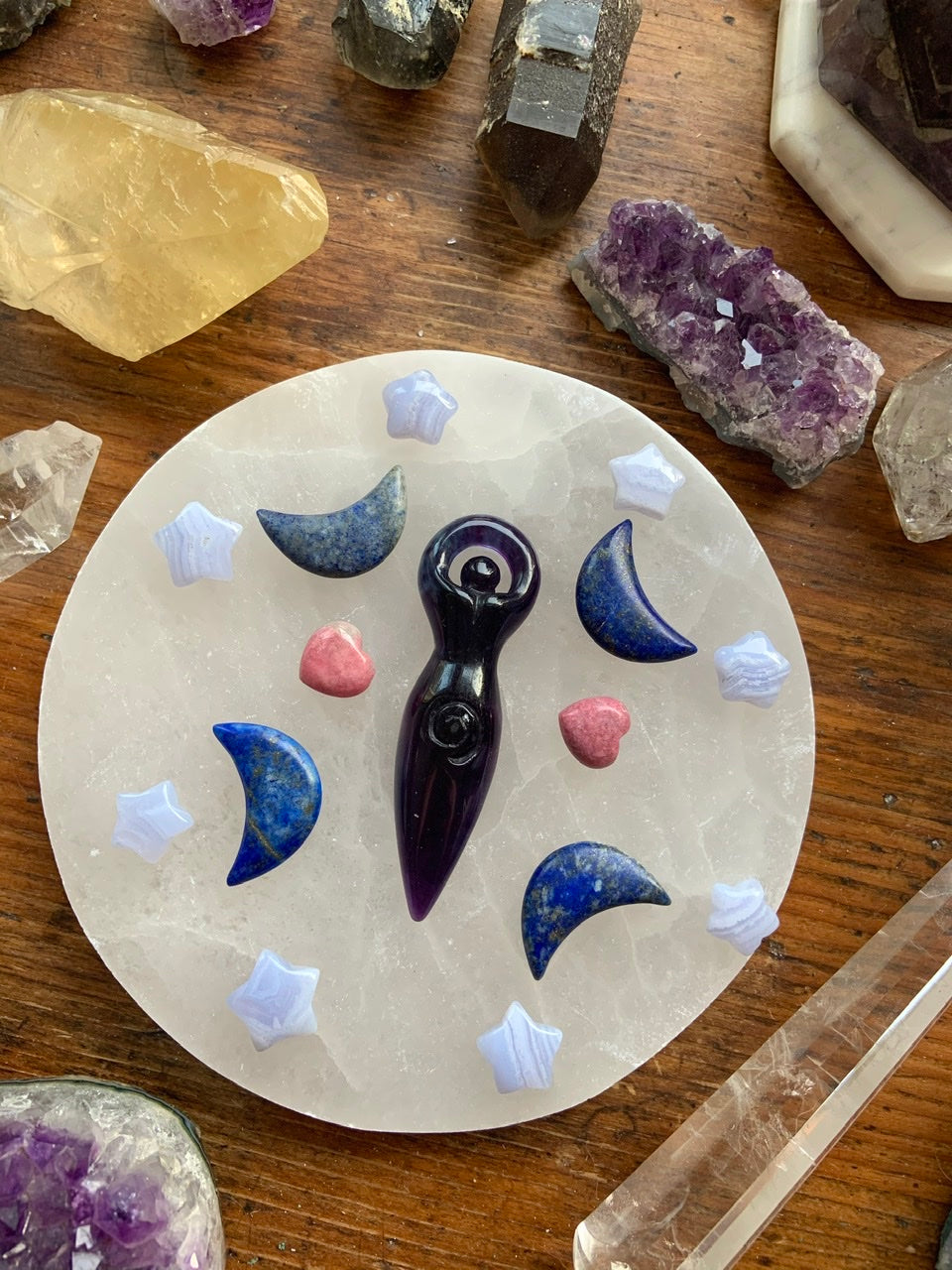Crystal grid with Blue Lace Agate stars, moon carvings, & a goddess carving in the center — sacred layout for emotional healing & divine alignment.
