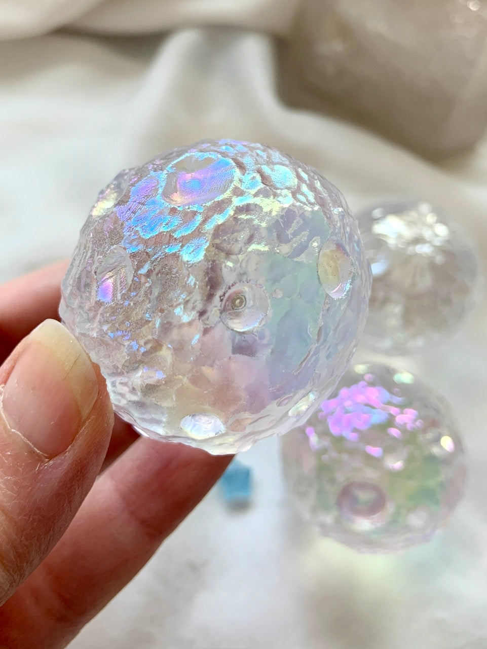 Close-up of Angel Aura Full Moon sphere showing cratered texture &amp; iridescent sheen — a radiant quartz carving inspired by lunar topography.