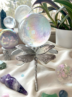 Elegant art deco inspired Dragonfly Sphere Stand shown with an aura quartz sphere in a crystal display with plants. Available in silver or gold finish, fits small to large spheres