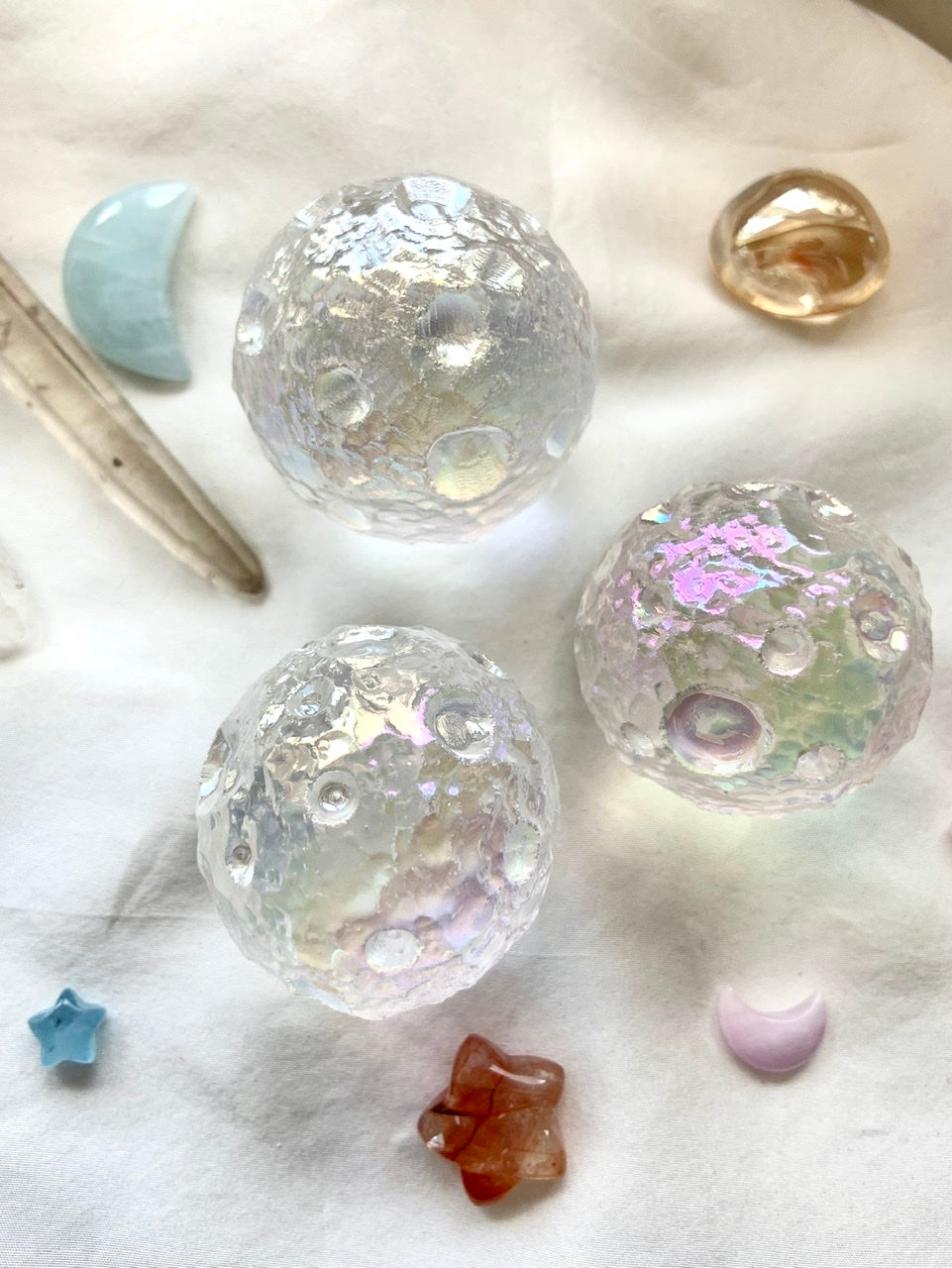 Trio of Angel Aura Full Moon spheres with mini kunzite moon, aquamarine moon &amp; quartz points on white silk — cosmic crystal arrangement for divine energy.