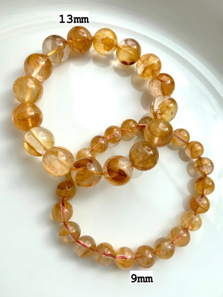 Golden Healer bracelets on a white plate, labeled with 13mm and 9mm bead sizes for comparison