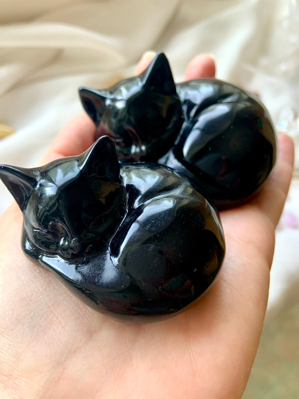 Two sizes of Black Obsidian Cat figurines shown in hand for scale — protective crystal keepsakes for cat lovers & memorials.