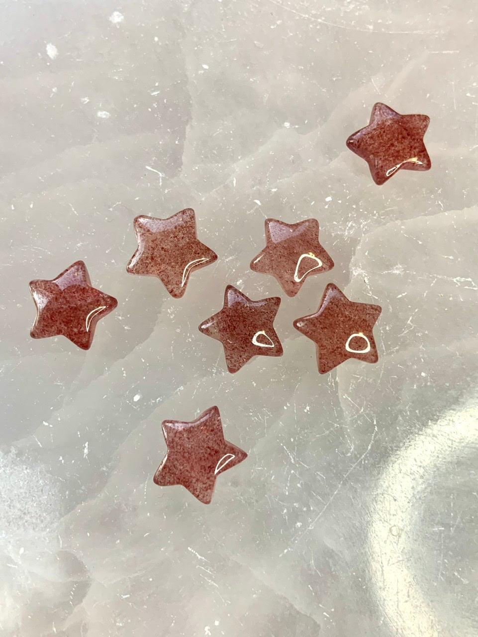 Mini Strawberry Quartz stars displayed on white selenite — joyful heart chakra carvings for altar, crystal grid, or gifting