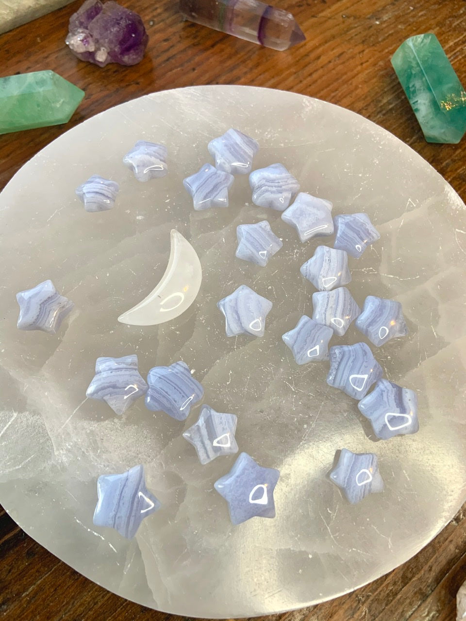 Blue Lace Agate stars displayed on a white selenite plate with a white crystal moon — soothing stones for peace, harmony & throat chakra healing.