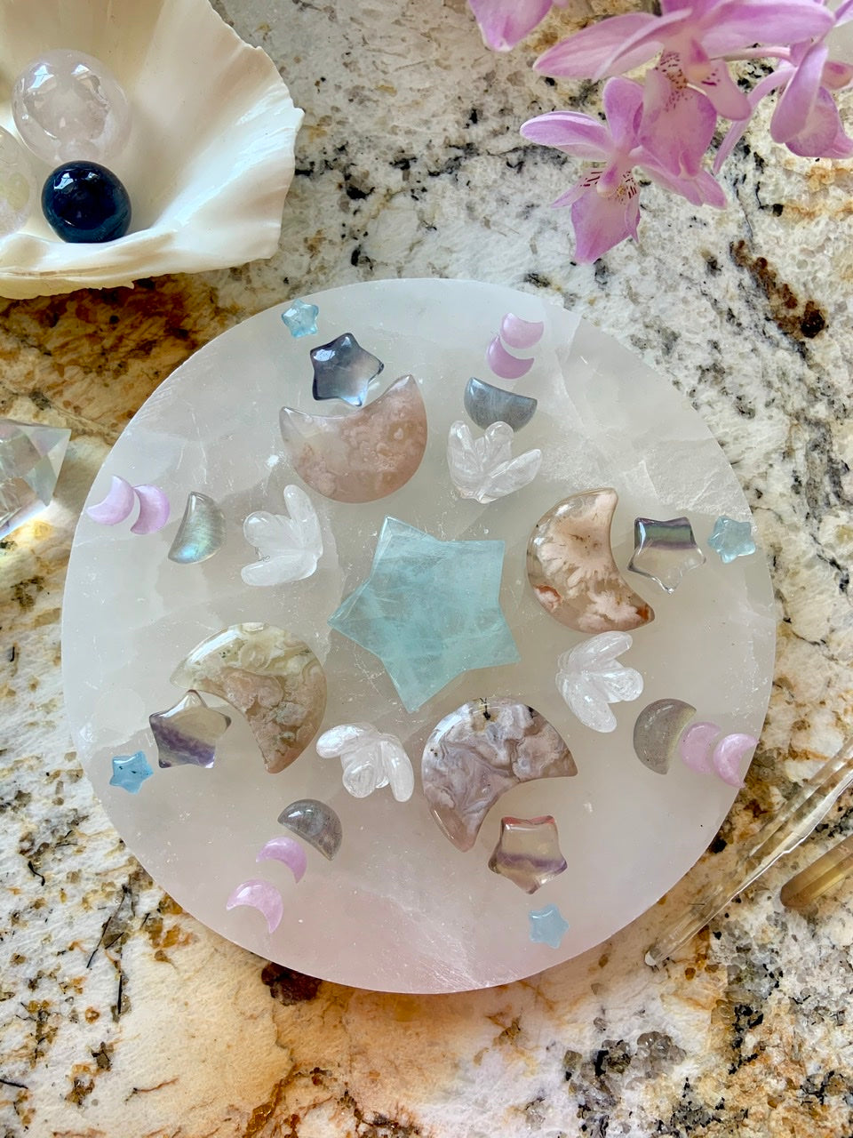 Crystal grid with mini Kunzite moons, Flower Agate moons & Aquamarine star on a selenite plate — a sacred layout for emotional healing, flow & intuition.
