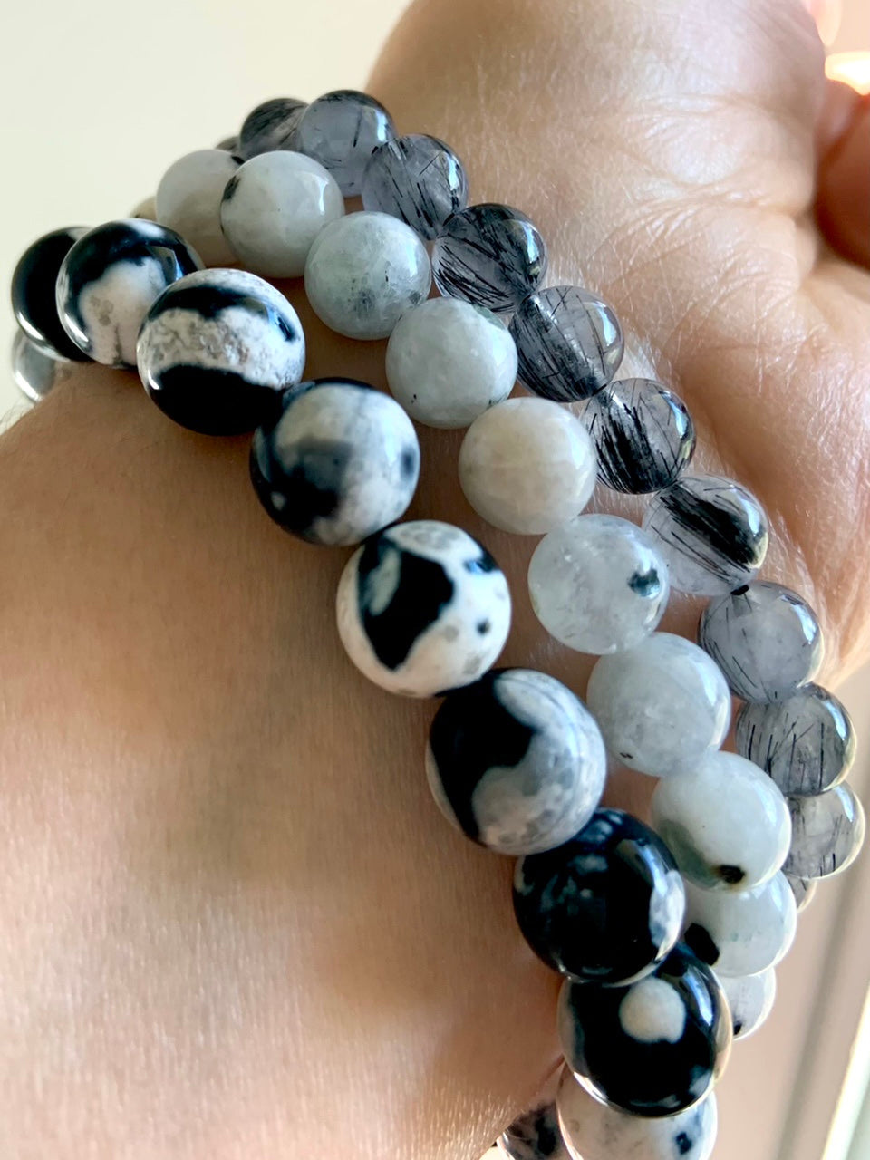 Mixed crystal bracelet stack with Orca Agate, Rainbow Moonstone, and Black Tourmaline in Quartz worn together for layered energy