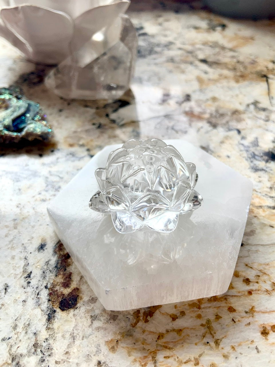 Side view of polished Selenite Hexagon Charging Plate with clear quartz lotus carving placed on top