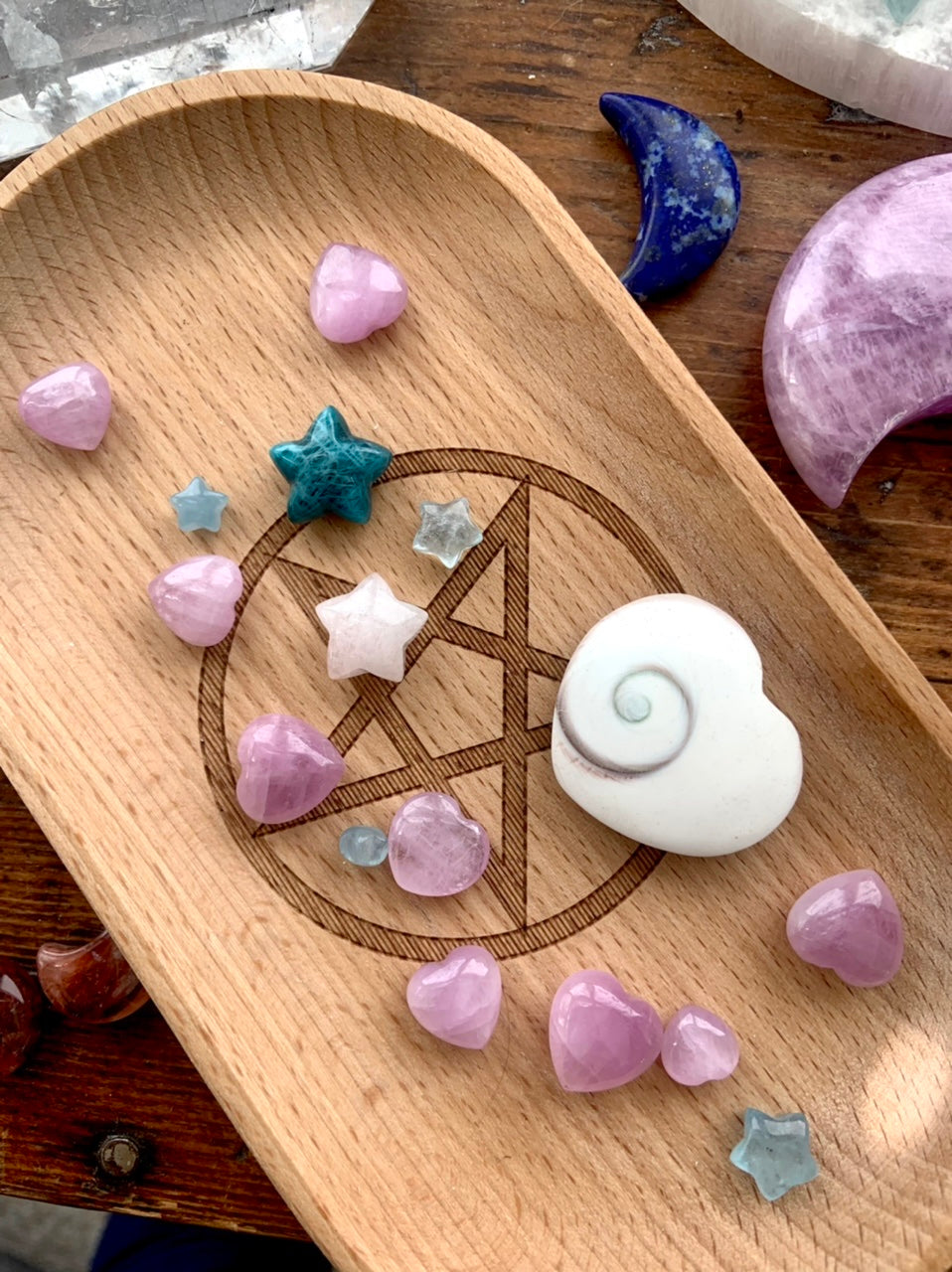 Wooden tray with assorted celestial crystals, featuring mostly Mini Pink Kunzite hearts — sweet pink stones for emotional healing & spiritual connection.