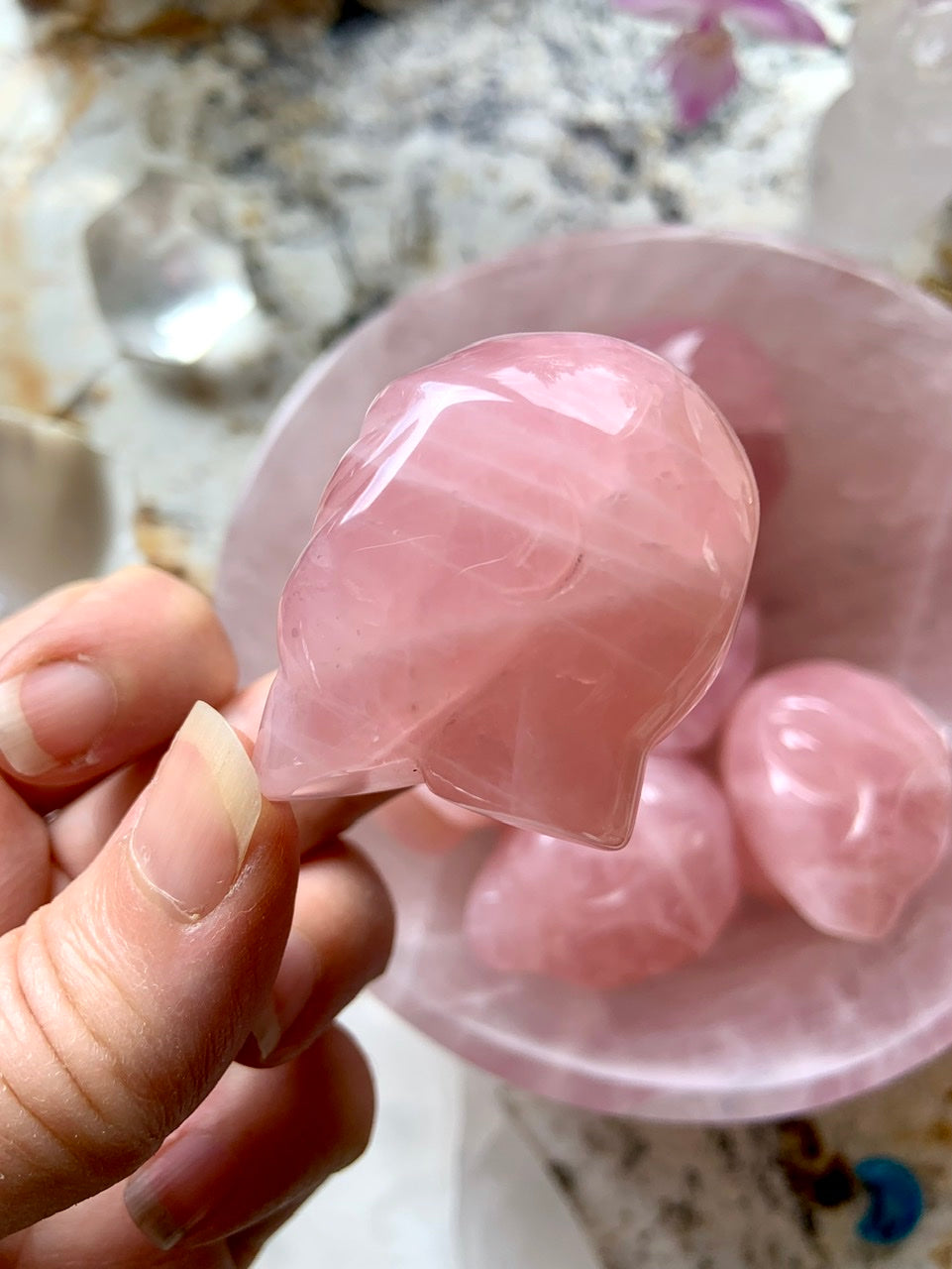 Side view of carved Rose Quartz alien head crystal with smooth finish and curved detail