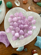 Clear Quartz heart bowl filled with Mini Pink Kunzite hearts, surrounded by other crystals — high-vibe crystal arrangement for love & heart chakra healing.