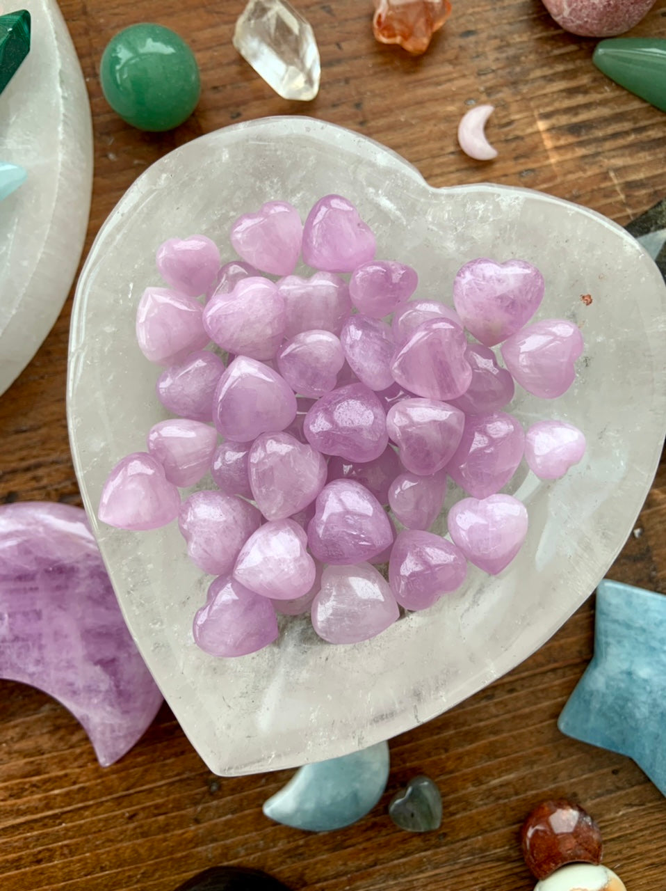 Clear Quartz heart bowl filled with Mini Pink Kunzite hearts, surrounded by other crystals — high-vibe crystal arrangement for love & heart chakra healing.