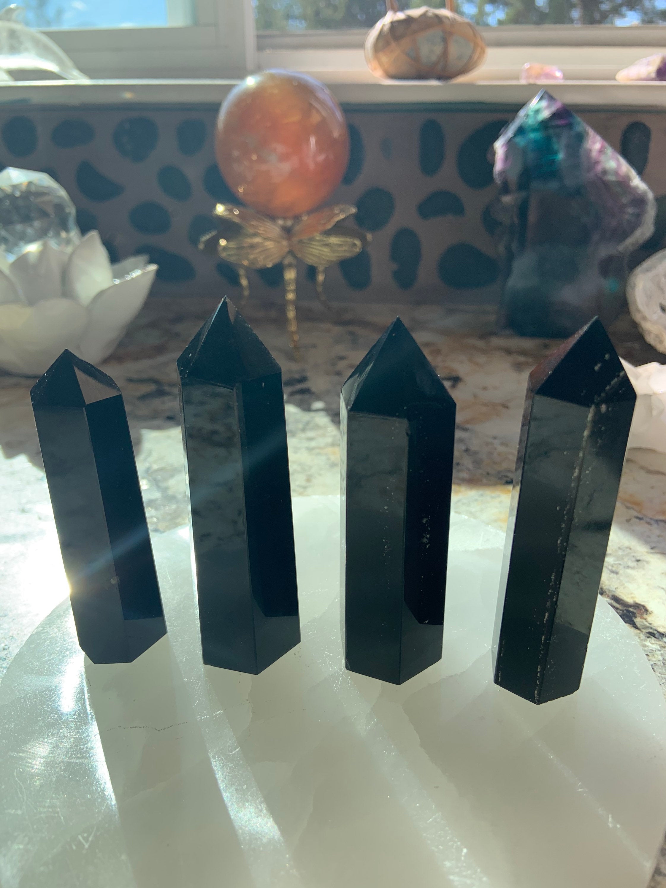An array of black obsidian points shown in a group on top of a selenite plate 