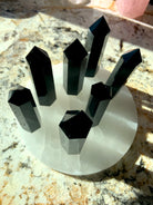 An array of black obsidian points shown from above, on top of a selenite plate