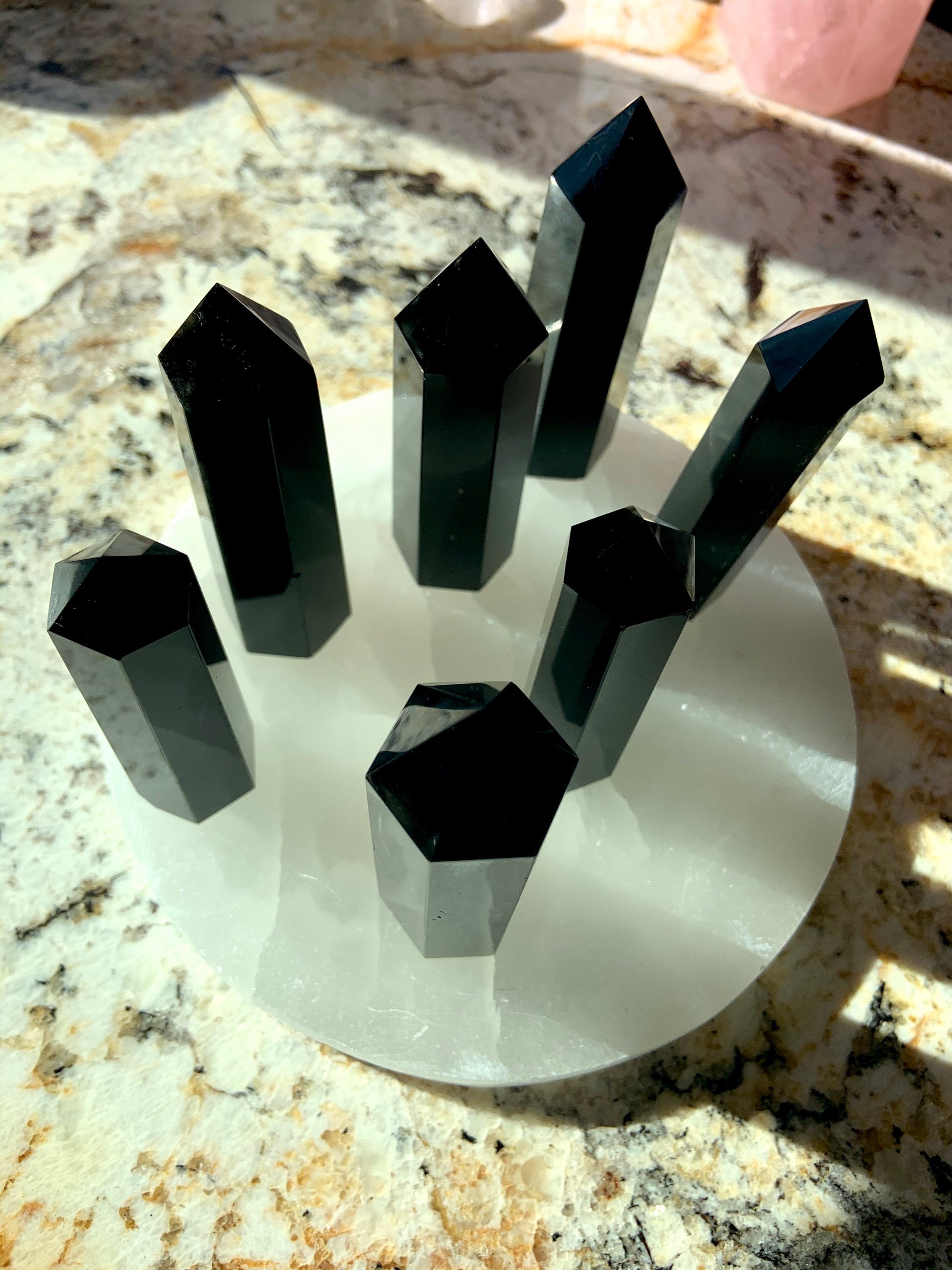 An array of black obsidian points shown from above, on top of a selenite plate