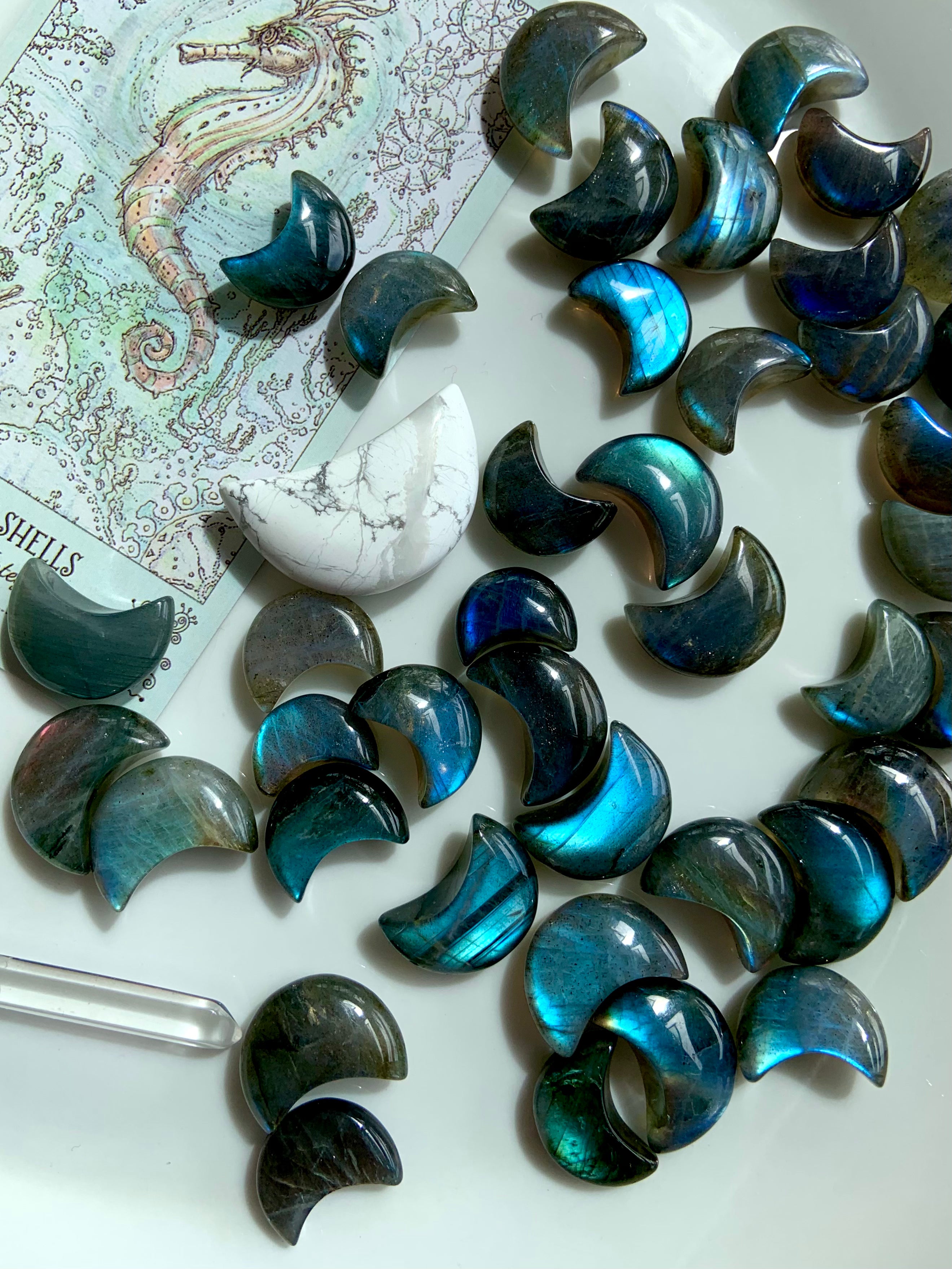Close-up of Labradorite crescent moons with tarot card, howlite moon & quartz point — intuitive crystal tools for Third Eye activation & divination.