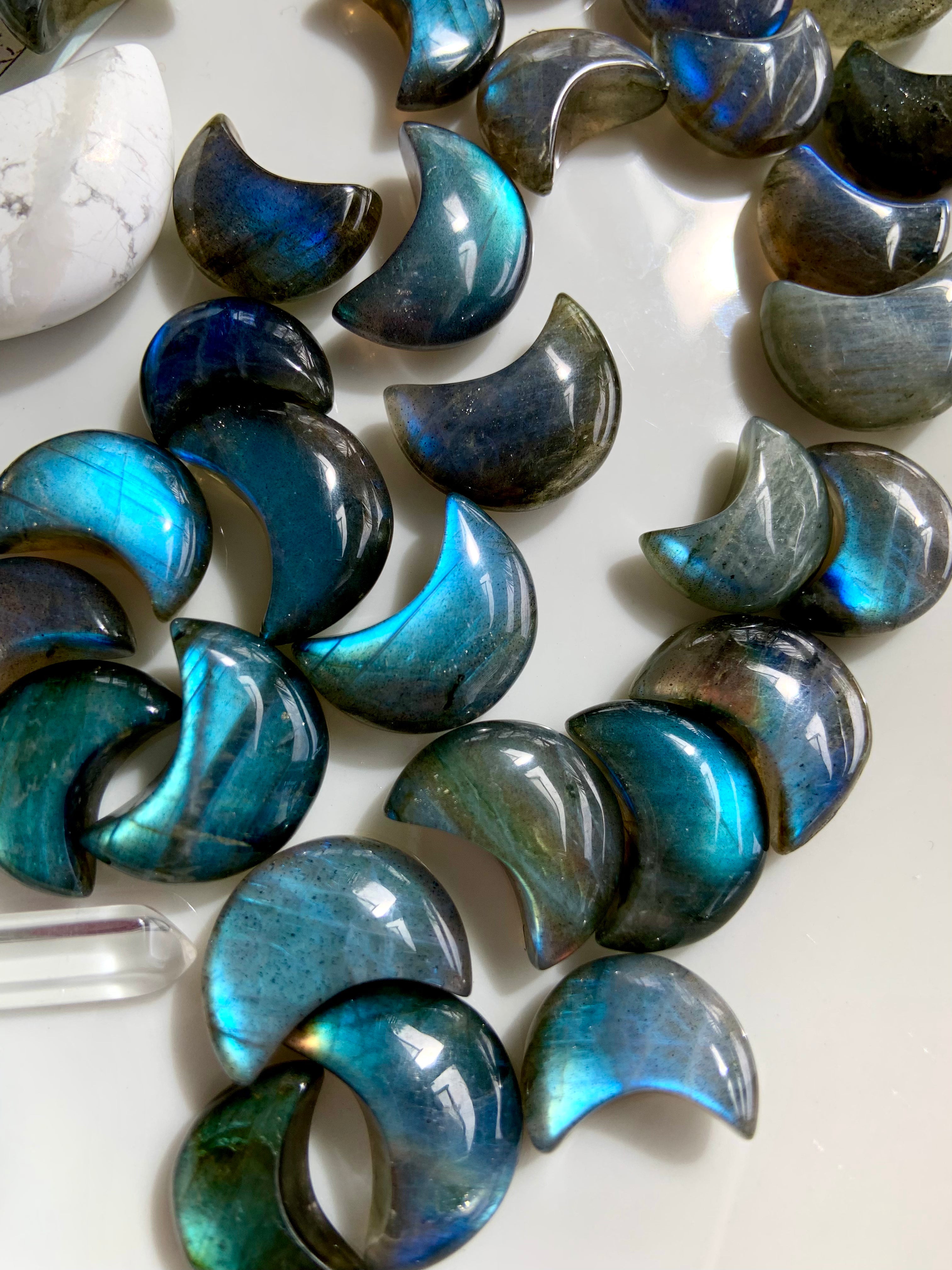 Deep blue Labradorite mini crescent moon carvings shown close-up on white — glowing Third Eye crystals for intuition, insight & energetic protection.